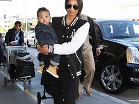 Ciara  Ciara holding her baby while wearing black high top chucks.