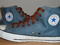 Denim Chuck Taylors  Inside patch views of light blue coated denim high tops with brown laces.