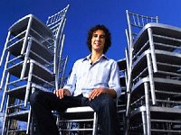 Josh Groban  Josh seated on a stack of chairs.