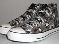 Chucks With Repeated Logo Pattern Uppers  Angled side view of black and white repeat ankle patch print high tops with black and white reversible shoelaces.