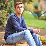 Teen Boys Wearing Chucks  Teen seated on brick garden steps wearing a long sleeved pullover shirt, faded blue jeans, and black high top chucks.
