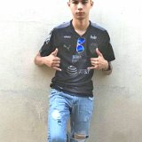 Teen Boys Wearing Chucks  Teen standing against a wall wearing a black logo tee shirt, torn and frayed blue jeans, and optical white low top chucks.