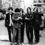 The Strokes  A black and white photo on the street, with several members wearing black or American flag print chucks.