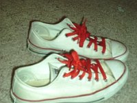 White Low Cut Chucks  Side view of worn optical white low cut chucks with red shoelaces.