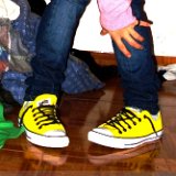 Yellow Chucks  Wearing neon yellow low cut chucks with black shoelaces, front view.